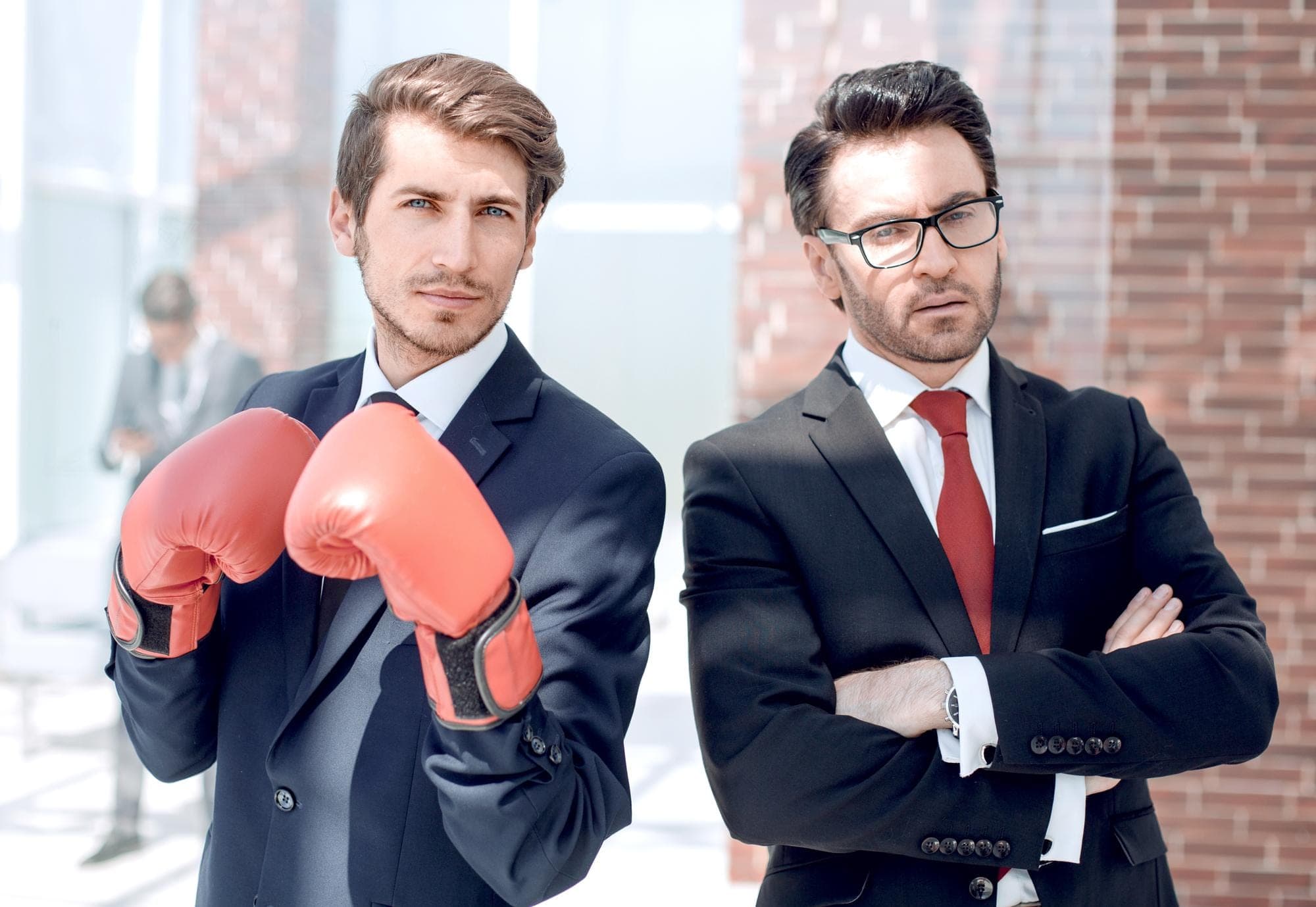 Two businessmen in suits, one with boxing gloves, symbolizing ABN vs ACN business choice.
