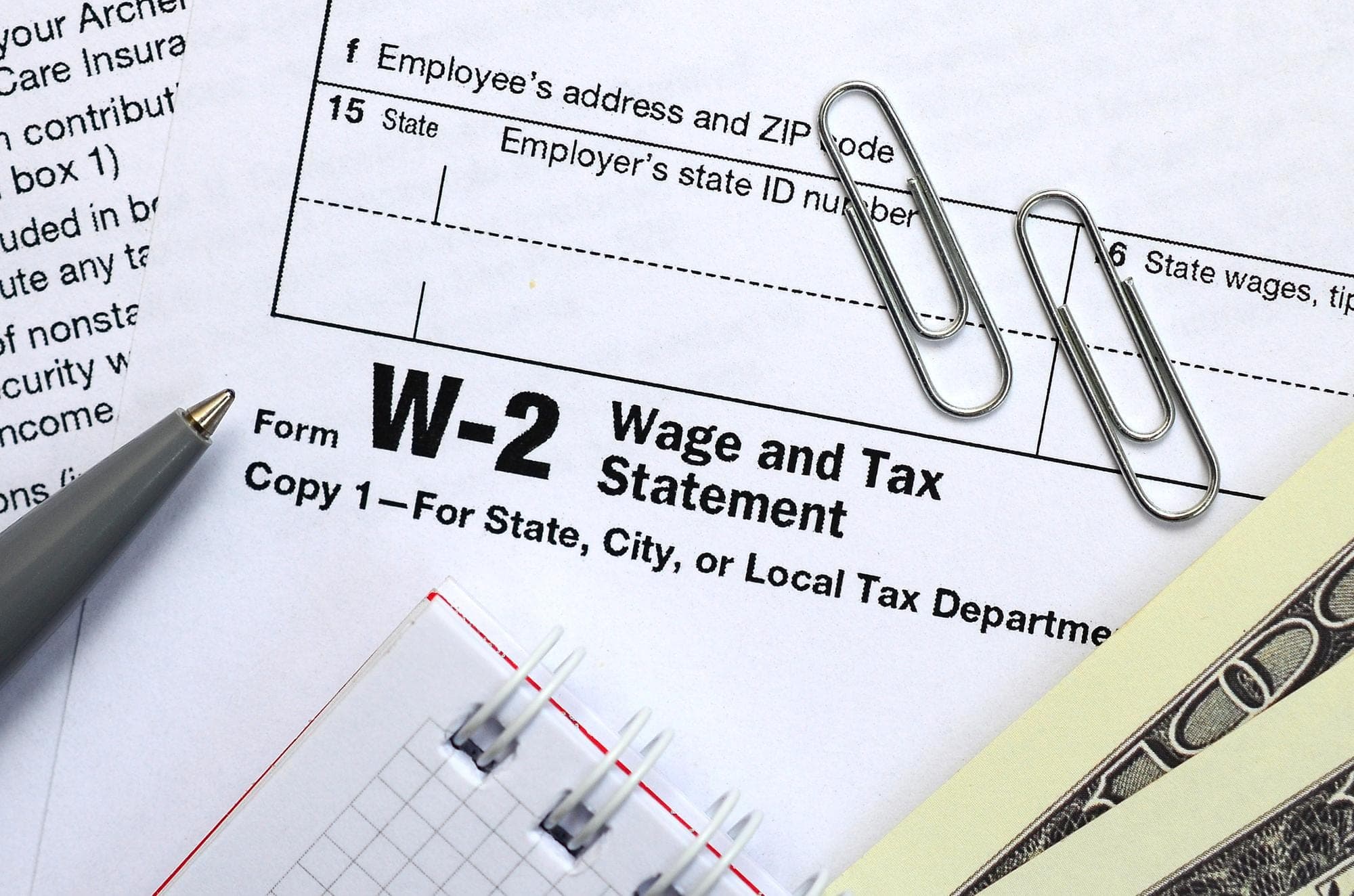 Wage and tax statement form with pen and paperclips related to company tax rate.