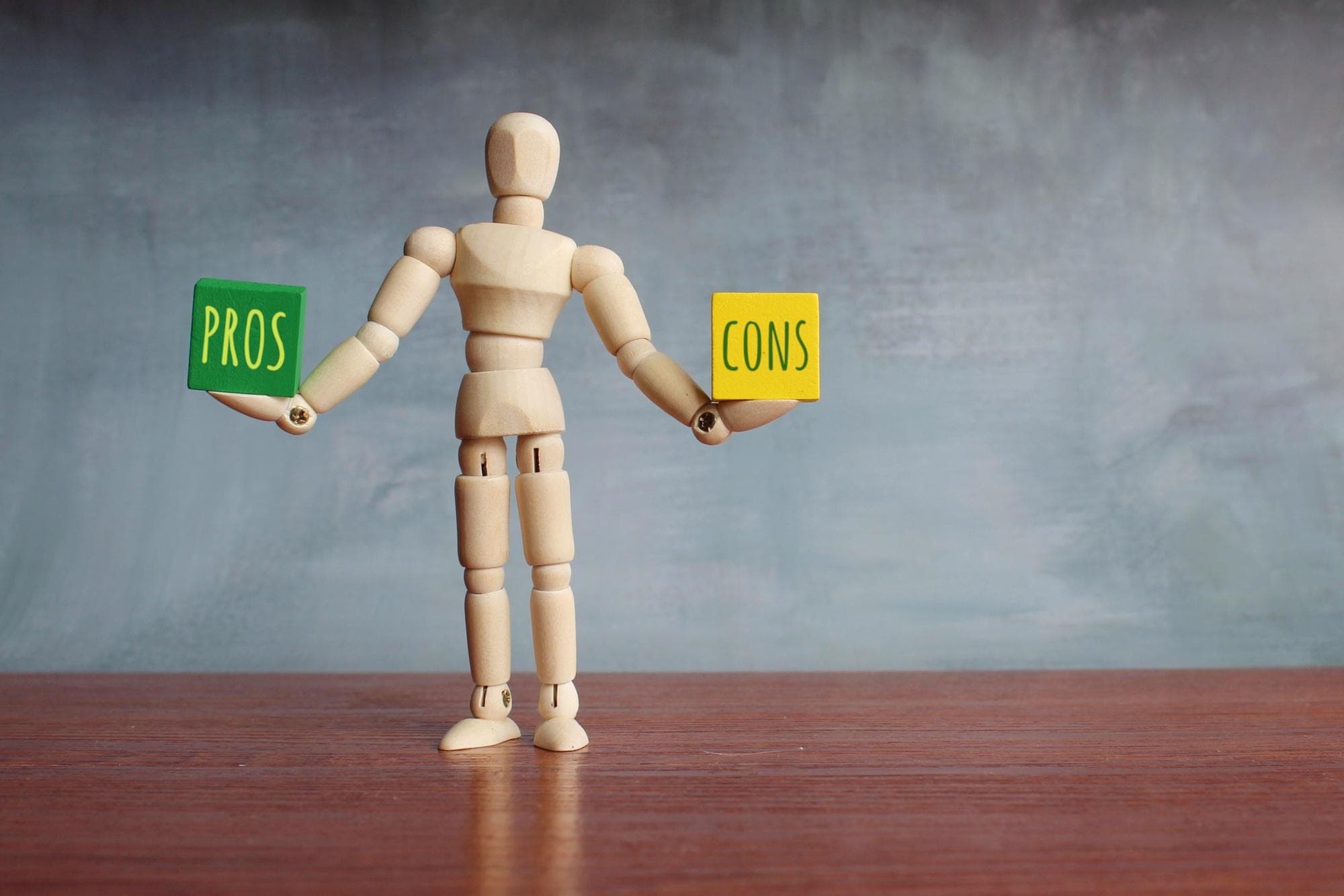 Wooden figure holding pros and cons signs for IAS vs BAS.