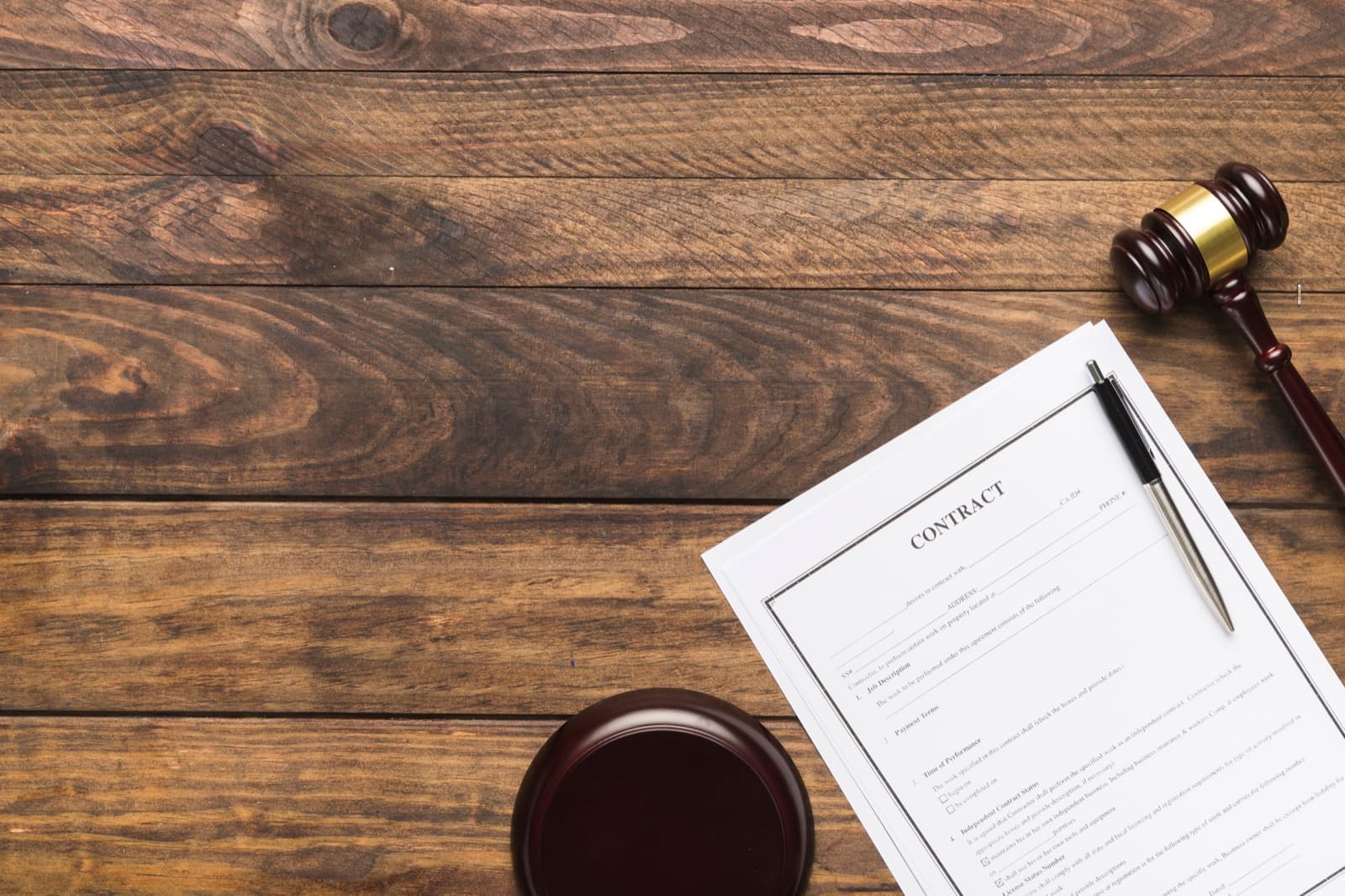 A wooden gavel beside a contract on a desk