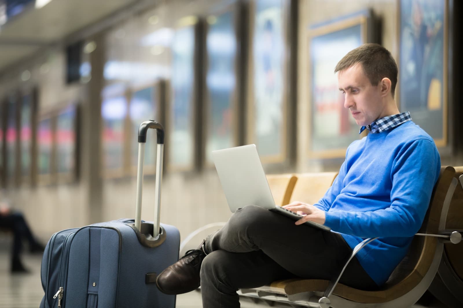 A traveller working on a laptop at a transport terminal