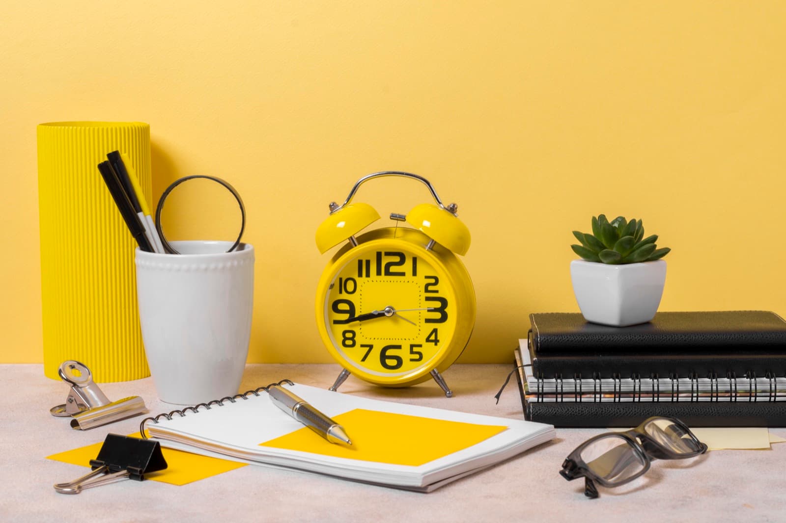 An alarm clock on a desk beside a workspace
