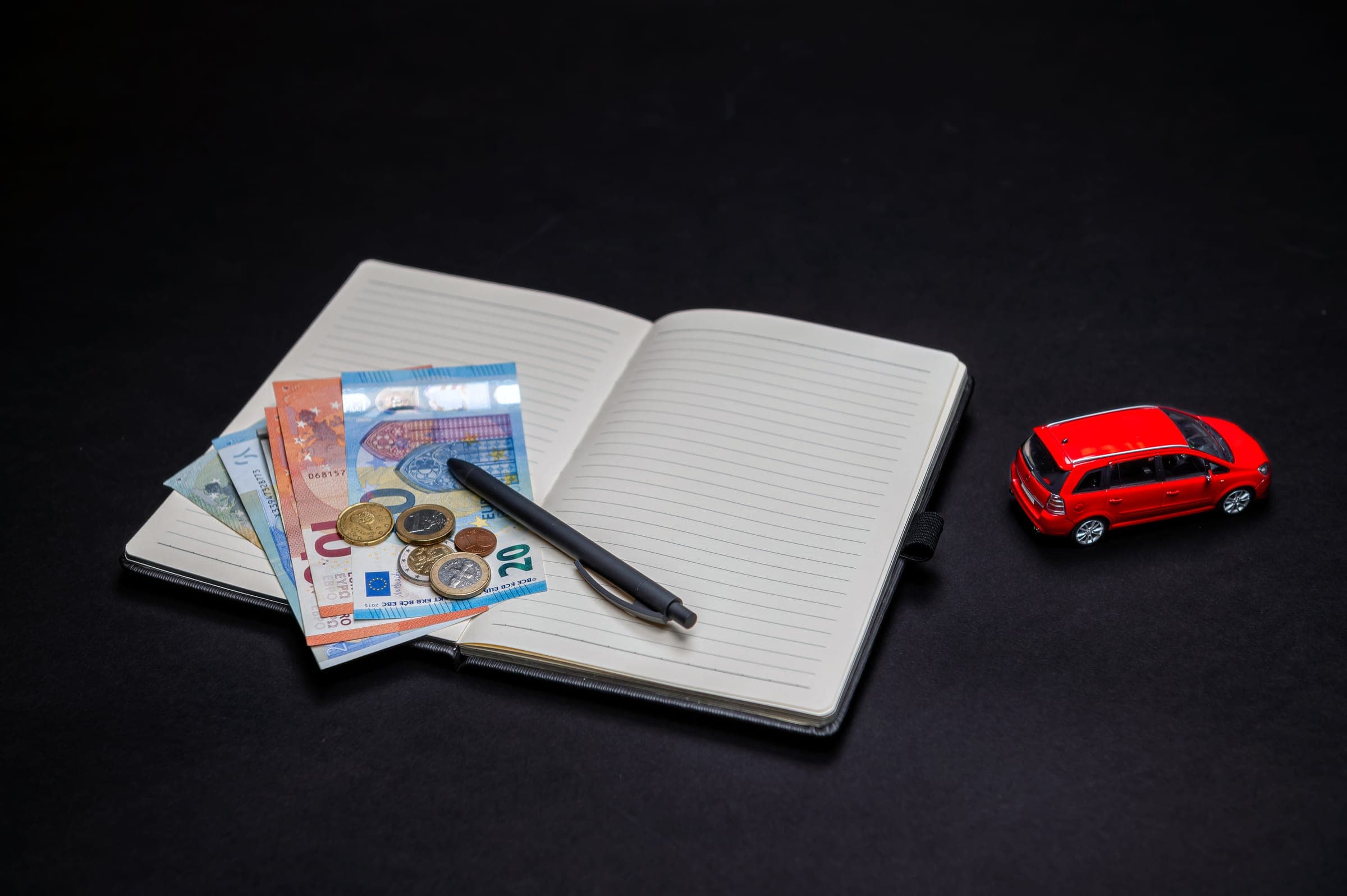 Euros, notebook, pen, toy car for car deduction topic.
