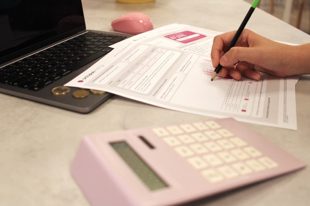 Person working with documents, calculator, and laptop, choosing bookkeeper or accountant