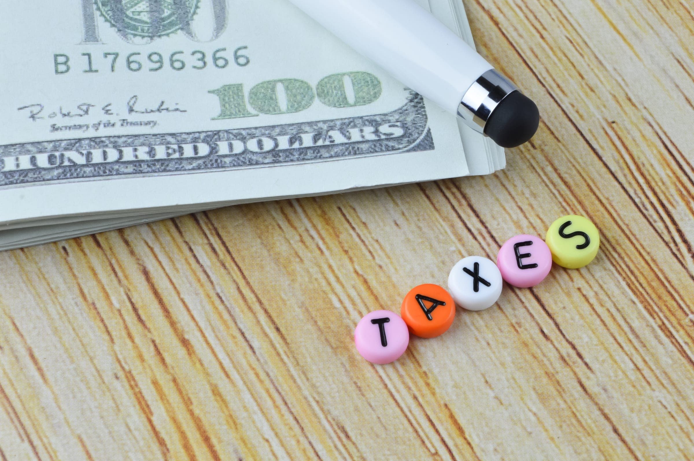 Cash and 'TAXES' beads concept for Division 296 tax impact.