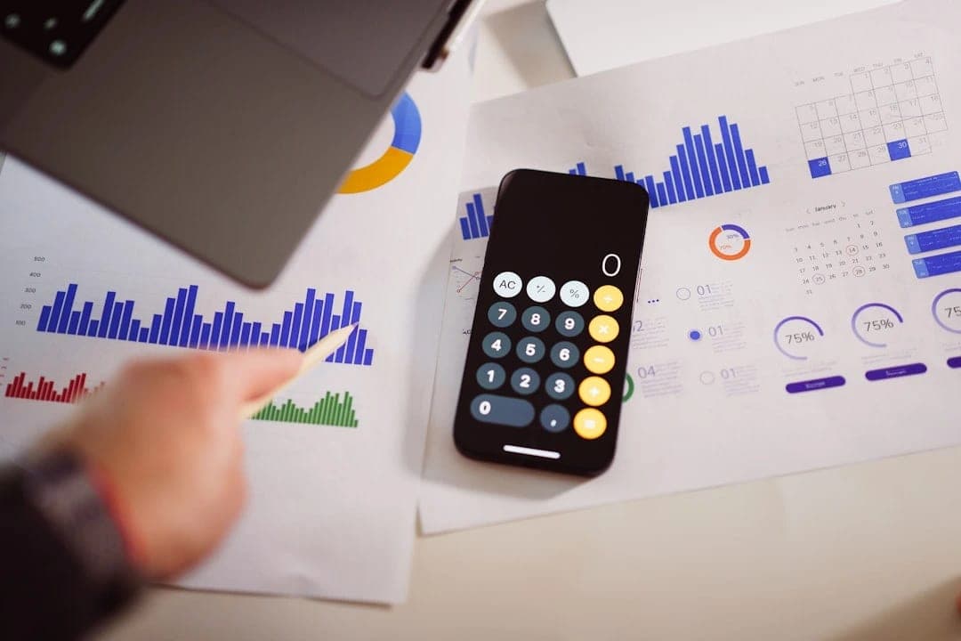 Smartphone calculator on financial charts showing profit margin analysis for Australian businesses