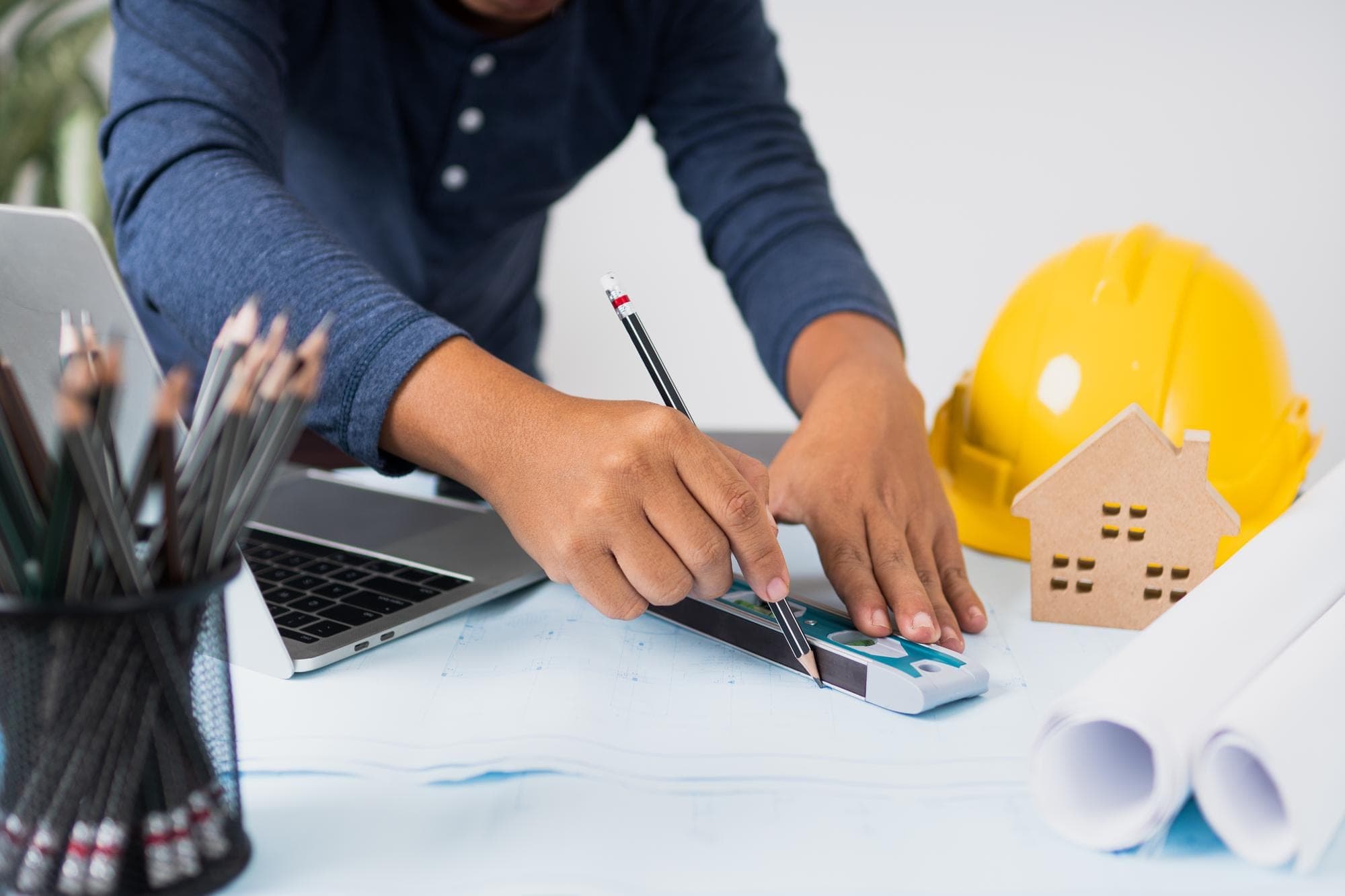 Contractor calculating with laptop and plans, focus on income rules.