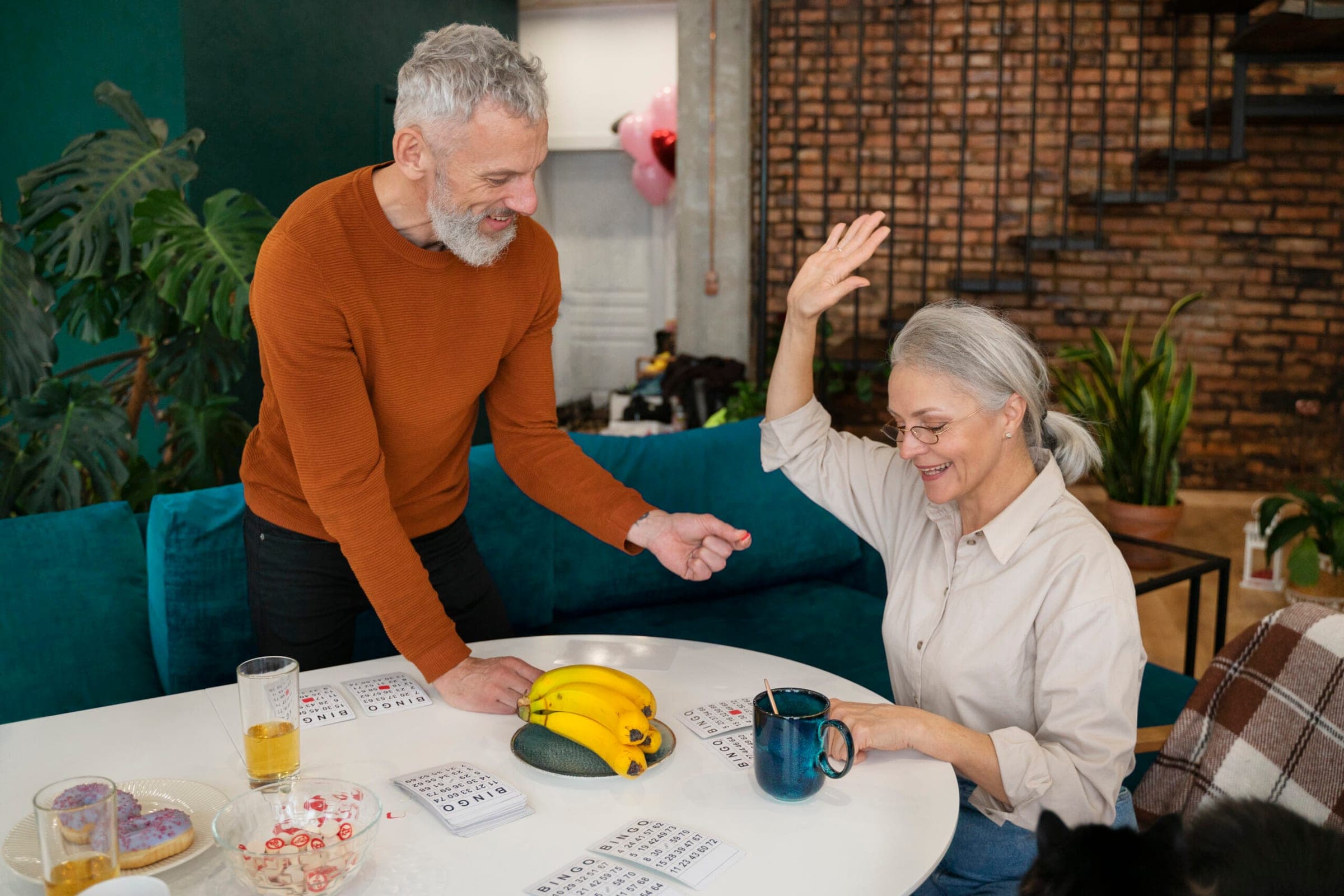 Happy senior couple enjoying retirement at home with snacks and drinks in Australia.