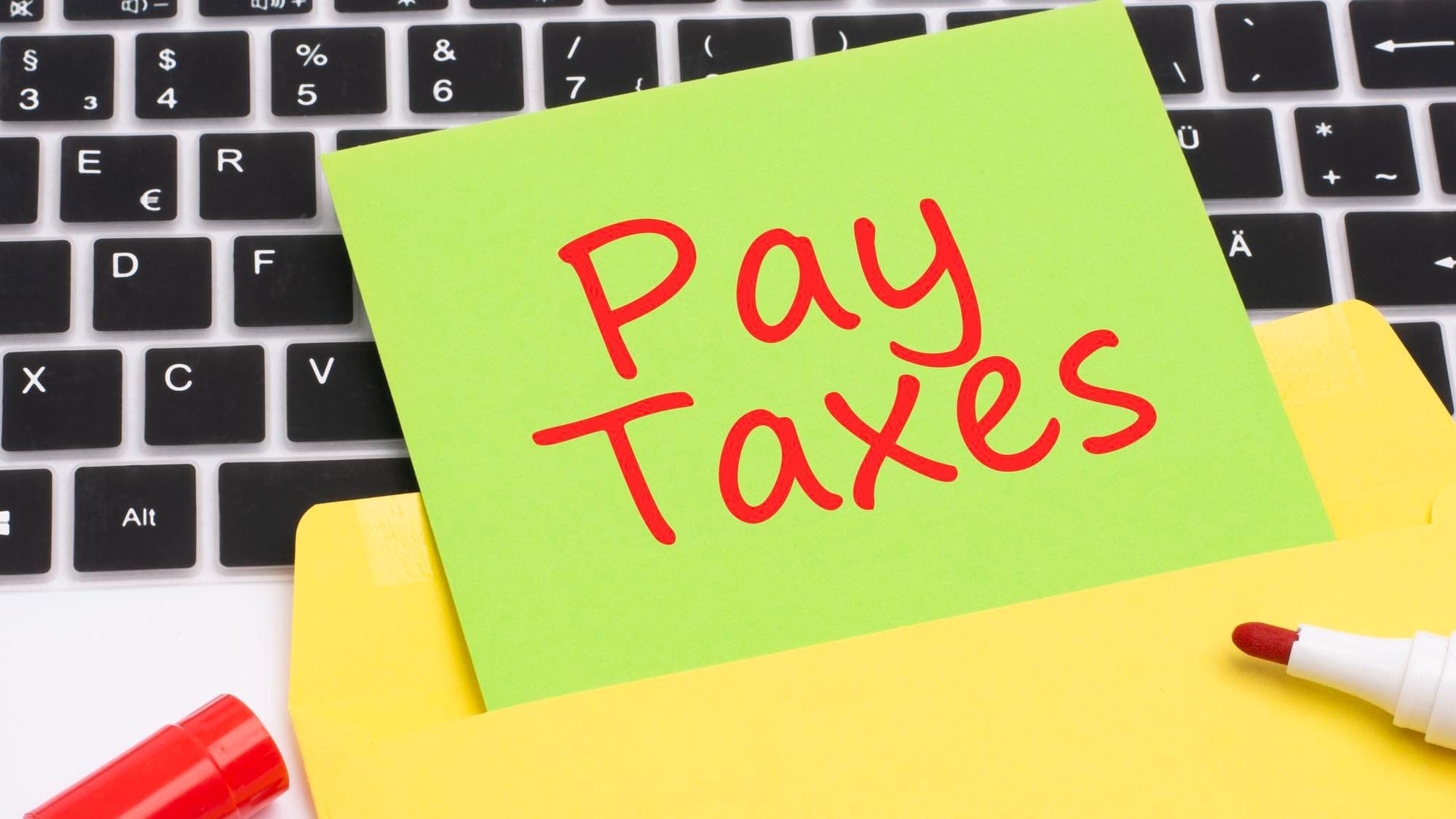Sticky note on keyboard reading 'Pay Taxes' related to STSL Tax topic.