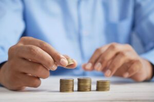 Parent drops a coin into a clear jar labelled “Education Fund”, symbolising an investment bond growing for a child’s future schooling costs