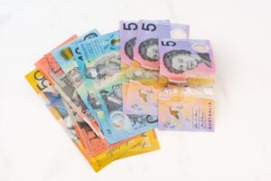 A fan of Australian polymer banknotes (including $50, $20, $10, and $5 notes) representing taxable income for 2025-26 tax bracket calculations.
