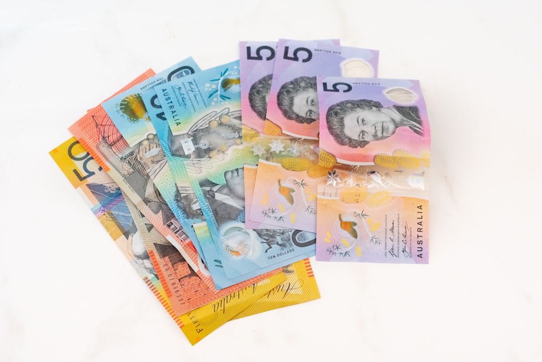 A fan of Australian polymer banknotes (including $50, $20, $10, and $5 notes) representing taxable income for 2025-26 tax bracket calculations.