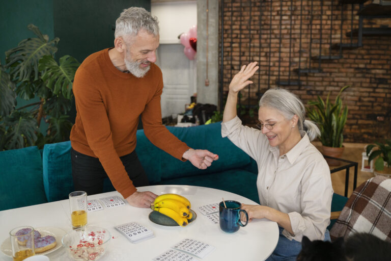 Happy senior couple enjoying retirement at home with snacks and drinks in Australia.