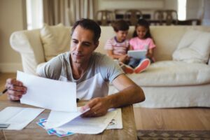 Man reviewing family trust documents at home in Australia with children nearby