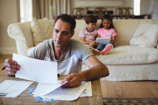 Man reviewing family trust documents at home in Australia with children nearby
