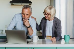 Older couple discussing finances at laptop, considering retirement planning options