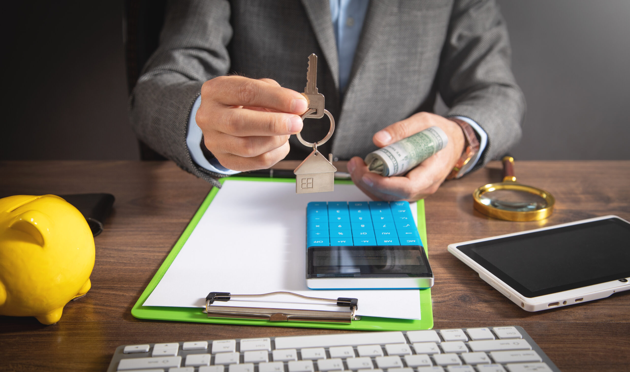 Man holding house key and calculator by tablet, symbolizing PAYG withholding variation for AU contractors.